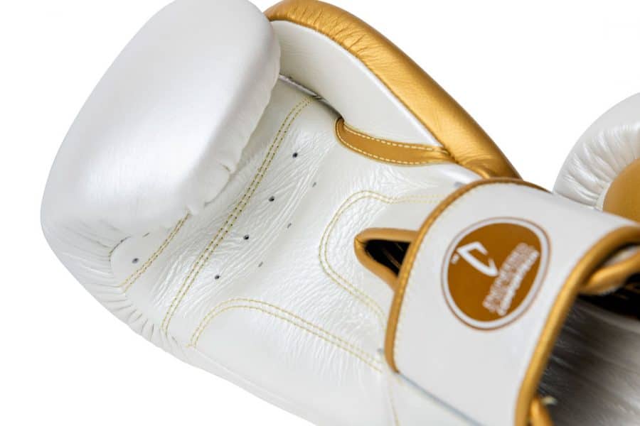 Corbetti CTG-005 Pearl White - Gold Muay Thai Glove palm side up highlighting full grain leather detail in palm with blurred out comfortech technology label
