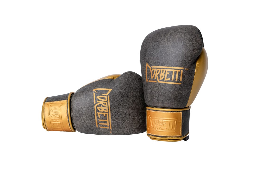 Corbetti CTG-006 Vintage-Gold Muay Thai Gloves right hand is laying down on its side and the left hand is standing up both displaying the fist side brand logos