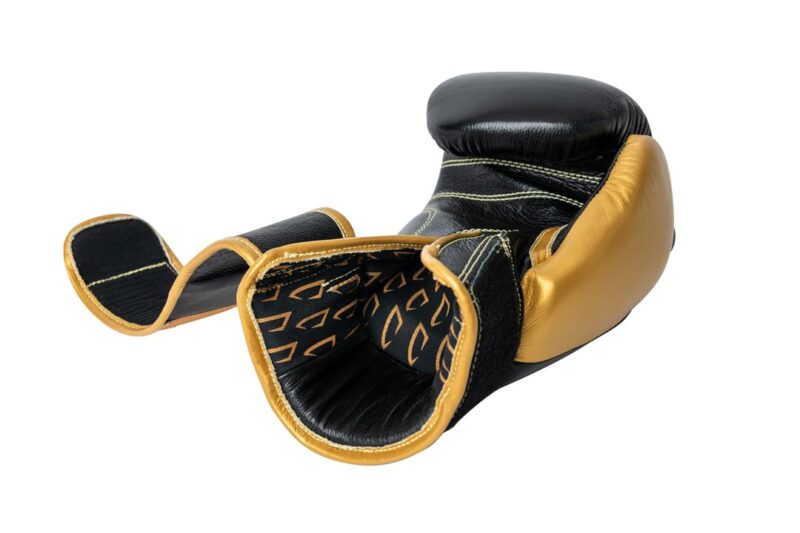 Corbetti CTG-001 Black-Gold Muay Thai Glove laying on fist side with palm up view of the inside of the glove showcasing the printed liner