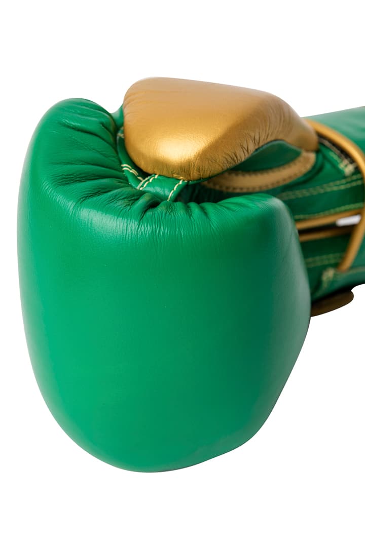 Corbetti CTG-003 Green-Gold Muay Thai Glove fist laying on its side fist forward showing beautiful metallic gold thumb and attachment detail